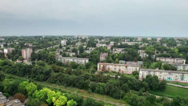 Вид с воздуха на маленький город, городской пейзаж, пролетающие мимо домов рядом с зелеными пространствами — стоковое видео