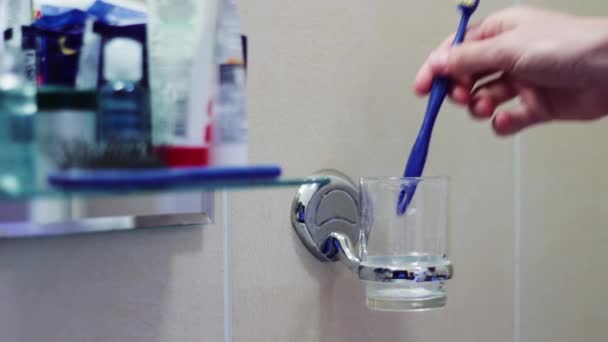 El hombre pone cepillos de dientes en un vaso — Vídeo de stock