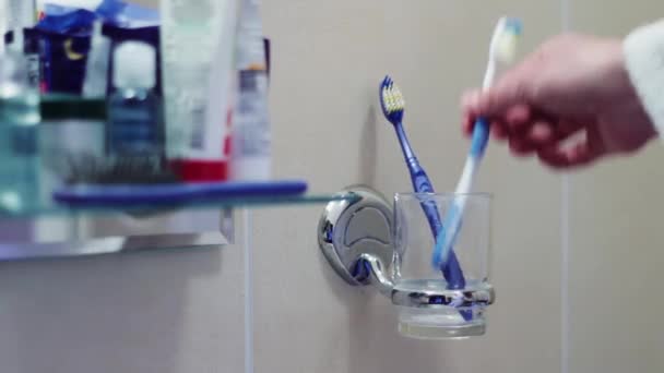 Чоловік кладе зубні щітки в склянку — стокове відео