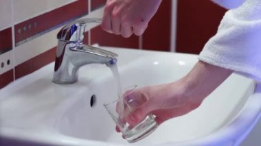 Adam bir bardak musluk suyu su toplar