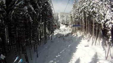 Kayakçı kayak teleferiği üzerinde yükselir. Panorama ve dağlar, ağaçlar karla kaplı manzara çevresinde. Teleferik göster.