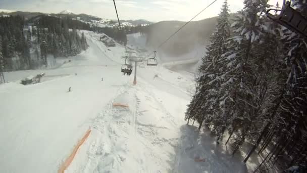 滑雪者在滑雪升降机升起。各地全景和风景的山脉，白雪覆盖的树木。查看从滑雪缆车. — 图库视频影像