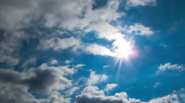 Mavi gökyüzünde parlak güneşin arka plan üzerinde hareket bulutlar.