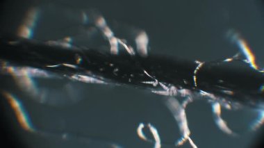 Koyu alan mikroskopisi olan aşırı yakın plan iplik iplikleri. Spektral renkler ve gökkuşağı yansımaları sentetik materyal üzerindeki ışık kırılması soyut bir model oluşturur, hareket eden odaklanma