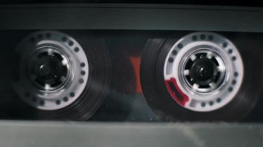 Eski bir ses kaydının yakın çekim görüntüleri çalma sırasında dönen şeffaf makaralar. Klasik analog ortam biçimi içinde soldan sağa doğru koyu manyetik bant makaraları