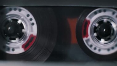 Bir ses kasedinin içinde dönen gümüş makaraların makro görüntüsü. Koyu manyetik bant çalma sırasında çözülür ve 80 'lerin modası analog teknolojisinin mekanizmasını detaylandırır..