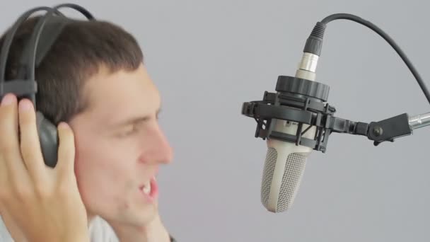 Hombre con auriculares cantando en el micrófono del estudio . — Vídeo de stock