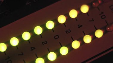 Ses karıştırıcının makro açısı LED seviye göstergesi titreşiyor. Sarı ışıklar, kırmızı tonlu ve desibel numaralı ses düzeyini karanlık bir stüdyo ortamındaki panelde gösteriyor..