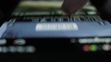 Bir parmağın mobil uygulama beslemesinden hızlıca geçmesinin makro perspektifi. Parlak ekran karanlık bir ortamda parlıyor, geceleri hızlı bir içerik akışı ve çevrimiçi veri sörfü gösteriyor.