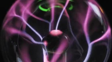 Pembe ve mor elektrik kavisli bir plazma küresi. Beyaz filizler, iyonize gaz cam küre içinde girdap oluştururken merkezi elektrottan yayılır. Fizik deneyi.