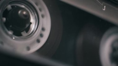 Açılı makro çekim klasik ses kasedi. Saydam makara işaretleri ile oynatılıyor. Analog ayarlarda siyah manyetik bant gevşetiliyor.