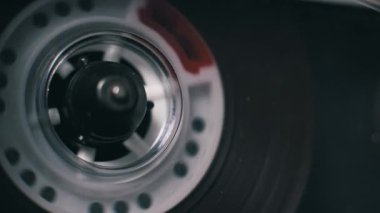Şeffaf plastik ve kırmızı işaretli, tek bir eski ses kaset makarasının makro yukarıdan aşağı görüntüsü bir teypteki koyu arkaplanda görünür..