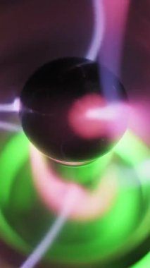 Merkezi plazma elektrotuna aşırı yakın çekim ve elektrik yayı boşaltımı. Pembe ve mor iplikler parlak yeşil bir tabanda bokeh ile ışıldıyor. Yüksek voltaj deneyi.