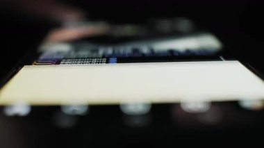 Sosyal uygulama haberlerinde dokunmatik ekranı sıyıran bir başparmağın aşırı yakın çekimi. Karanlık bir ortamda, ekran parmağı, hızlı kaydırma direklerini, fotoğrafları ve videoları aydınlatır. Kullanıcı deneyimi Kullanıcı Arayüzü.