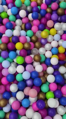 Yukardan manzara renkli plastik toplar top havuzunda hafifçe hareket ediyor. Pembe, mor, mavi, yeşil, beyaz, sarı ve altın küreli desen. Çocuk eğlencesi için bir oyun alanı, soyut şablon.