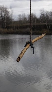 Ev yapımı ip, tahta bir sopayla sakin bir gölde yavaşça sallanıyor. Sahne bulutlu bir günde sessiz, ıssız ve melankolik bir atmosfere sahiptir..