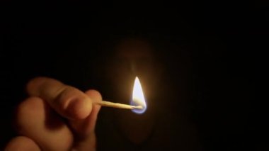 Yeni yakılmış ahşap bir kibrit çöpünü tutarken. Parlak, titreyen alev, karanlığı aydınlatır. Ilık, izole bir ışıltıyla, siyah bir arkaplanda..