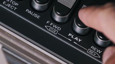 Parmak itme hareketinin ayrıntılı kenar açısı. Sonra da klasik bir kasetçalarda dur. Siyah çıkıntılı düğmeler ve krom aksanlar retro ses tasarımını vurgular.