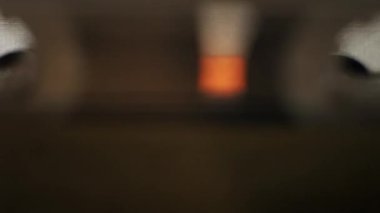 Eski bir cihazda çalan yıpranmış sarı ses kasetinin makro görüntüsü. Şeffaf makaralar, manyetik bant akarken teyp tezgahının arkasında döner..