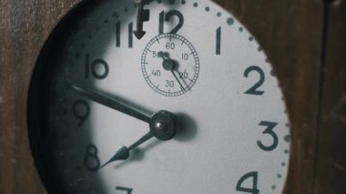 Eski bir analog saatin tozlu beyaz kadranlı aşırı yakın çekimi. İkinci el, ahşap bir çerçeve içinde zamanın geçişini işaretlemek için sürekli hareket eder..