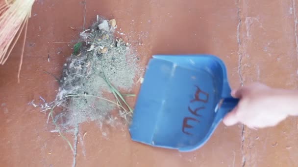 Fille avec un balai balaie les débris sur le sol et le jette dans la poubelle .