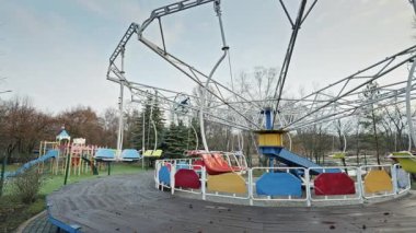 Sonbahar boyunca ıssız bir lunaparkta boş salıncak duruyor. Bulutlu gökyüzü ve çıplak ağaçlar kasvetli, melankolik bir atmosfer yaratıyor..
