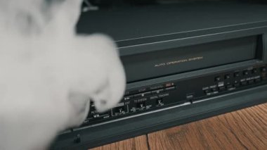 Antika siyah video oynatıcı ahşap rafta otururken kalın beyaz duman yayar. Yoğun sis, ağır arıza veya kısa devre gösteren elektronik aygıtı yutar.