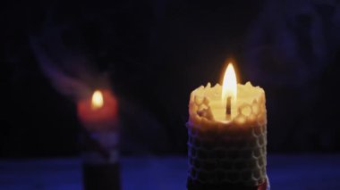 Balmumu desenli mum sönmeden önce parlak bir şekilde yanar ve koyu arkaplana doğru kıvrımlı beyaz duman izi bırakır. Ruhani ritüeller, rahatlama ve gizem kavramı.