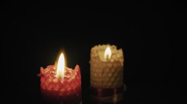 İki bal peteği bal mumu mumunun yakın çekimi. Yumuşak, titreyen alevlerle yanan koyu bir arka plan. Anma, romantizm, barış, maneviyat ve samimi ortam kavramı.