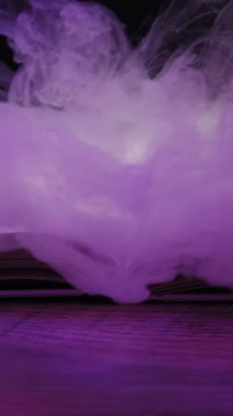 Açık bir kitap, mor ışıkla aydınlatılmış ahşap bir yüzey üzerinde yatar. Mistik duman sayfaların üzerinde kıvrılır. Sihirli büyüler, fantezi hikayeleri ve doğaüstü gizem kavramı..