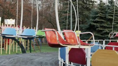 Renkli ama eski salıncaklı koltuklar boş bir eğlence parkında oturuyor. Kamera yavaşça uzaklaşıyor, yalnızlık ve çürüme hissini arttırıyor..