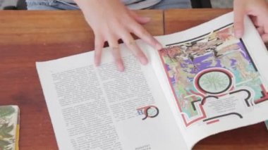 Masanın üzerine bir kitap aracılığıyla leafing kadın.