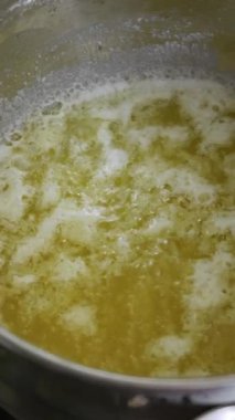 Sarı eritilmiş tereyağı ya da yağ fırının üzerindeki gümüş paslanmaz çelik tencerenin içinde hızla kaynıyor. Mutfak hazırlığı, pişirme malzemeleri ve tereyağı yapma kavramı..