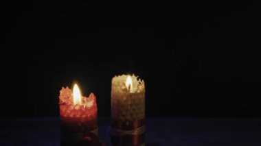 İki desenli balmumu mum zifiri karanlık arka planda yanıp sönen alevlerle ışıl ışıl yanar. Bir spa ortamında maneviyat, romantik atmosfer, dua ve rahatlama kavramı.