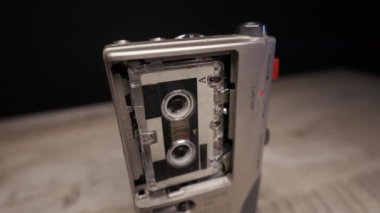 Gümüş analog ses kaydedici ahşap bir yüzey üzerinde dönen bant makaraları ve aktif kırmızı LED ışık ile çalışır. Retro gazetecilik kavramı, polis kanıtı, izleme ve klasik ses teknolojisi.