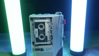 Gümüş renkli bir mikrokaset kaydedici dönen makaralarla ses kaydeder ve renkli ışıklara karşı kırmızı ışık yakar. Retro teknoloji, gazetecilik, izleme ve klasik ses kaydı kavramı.