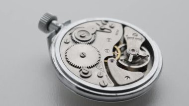 Eski bir mekanik cep saatinin dişlileri ve salınan denge çarklarını gösteren iç mekanizmasını yakın çekimde döndürüyorum. Karmaşık mekanizma tam olarak çalışıyor. Zaman yönetimi ve mühendislik kavramı.