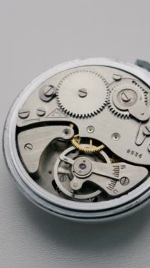 Antika bir cep saatinin gümüş vitesleri keskin detaylı makro çekimde ritmik olarak döner. Zaman yönetimi, hassas mühendislik ve nostaljik zanaat kavramı.