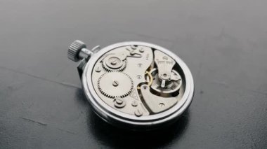 Genel bakış, karanlık bir yüzeyde dönen açık kaliteli bir cep saatinin karmaşık viteslerini ortaya çıkarır. Zaman kavramı, mekanik hassasiyet ve antika işçilik..