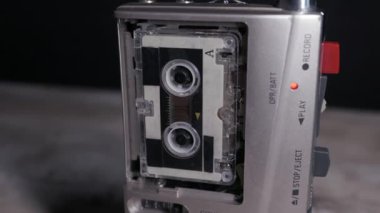 Gümüş mikrokasetçalar dönen makaralar ve karanlık bir ortamda kırmızı ışıkla çalışır. Eski gazetecilik kavramı, polis sorgusu, dikte ve analog gözetim.