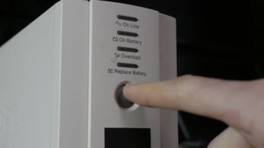 Bir parmak, UPS bataryasındaki güç düğmesine basarak sarı gösterge ışığını etkinleştirir. Veri koruması, acil güç kaynağı ve elektrik bakımı kavramı.