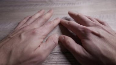 Bir adamın elleri ahşap bir masada dinlenirken hafifçe titrer ve titrer, birinci şahıs gözüyle bakıldığında. Anksiyete, stres, akıl sağlığı ve iç kargaşa kavramı.