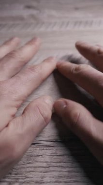 Bir insanın parmakları, yakın plan çekimde gergin bir şekilde kırsal ahşap bir masaya dokunuyor. Endişe kavramı, sabırsızlık, bekleme, stres ve derin düşünce.