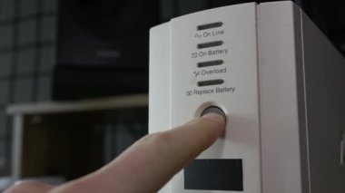 Kehribar ışığını aktif hale getirmek için beyaz bir kargo ünitesinin güç düğmesine basan bir parmağın yakın çekimi. Elektrik güvenliği, veri koruması ve ofis ekipmanları kavramı.