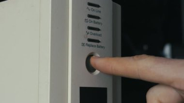 Parmaklama, beyaz kesintisiz güç kaynağı ünitesindeki güç düğmesine basarak turuncu gösterge ışığını etkinleştiriyor. Acil durum elektriği, sunucu bakımı ve donanım koruması kavramı.