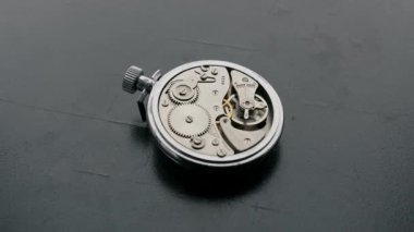 Açık gümüş bir cep saati mekanizması düzgün vites ve denge tekerleklerini ortaya çıkarmak için yavaşça döner. Zaman yönetimi, hassas mühendislik ve antika işçiliği kavramı.