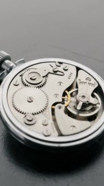 Gümüş mekanik kronometre hareketli dişlileri ve salınan denge çarkını ortaya çıkarmak için dönüyor. Zaman yönetimi, hassasiyet ve karmaşık endüstriyel mekanik kavramı.