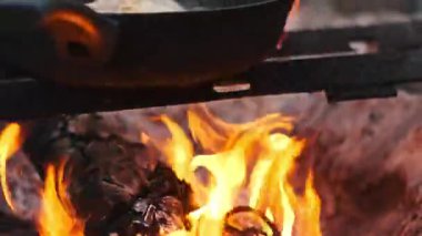 Parlak yanan bir kamp ateşinin yakınında canlı turuncu ve sarı alevler havada dans ediyor..