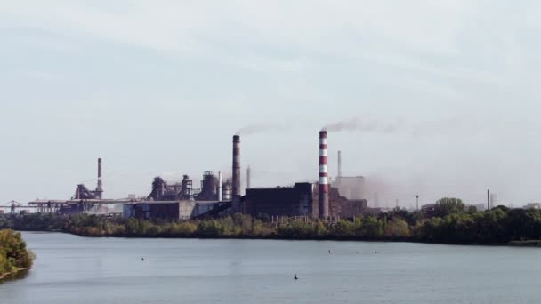 De fabriek aan de rivier, zware industrie, de rook van leidingen — Stockvideo