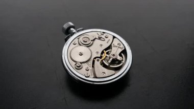 Bir makro zaman atlaması, klasik mekanik kronometrenin içindeki vites ve denge çarklarının hızlı hareketini ortaya çıkarır. Kavram, hassasiyet mühendisliğini ve geçen zamanın hızla ivmelenmesini gösteriyor.